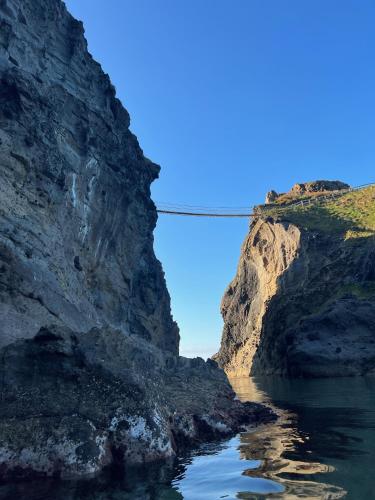 a bridge over a river between two rocky cliffs at Bayview Farm Holiday Cottages in Bushmills