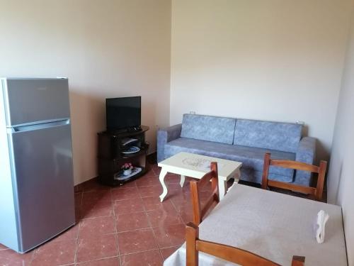 a living room with a couch and a table and a refrigerator at The Garden Guest House in Divjakë
