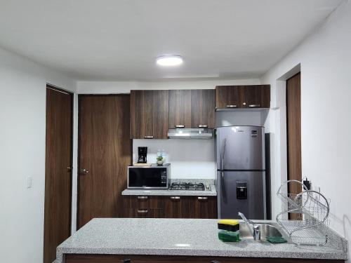a kitchen with wooden cabinets and a stainless steel refrigerator at Nuevo y amplio departamento con alberca y seguridad en el centro de Guadalajara in Guadalajara