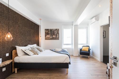 a bedroom with a large bed and a chair at Lisbon Airport Suites in Lisbon