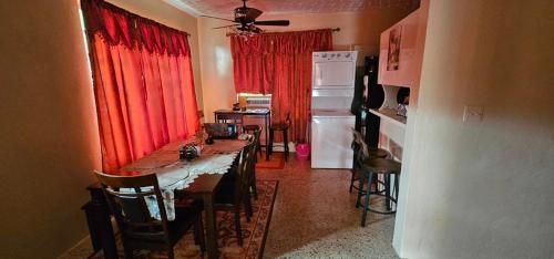 cocina con mesa, nevera y cortinas rojas en Smitty's Home Away From Home, en Carlota Amalia