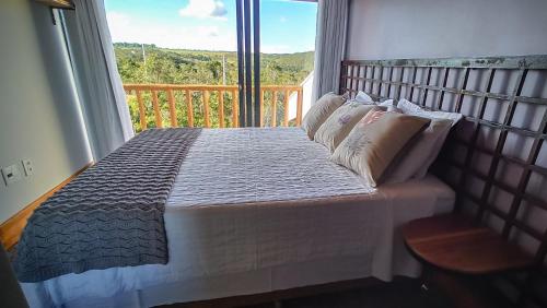 a bed in a bedroom with a large window at Vila Astra - jacuzzi privativa, natureza e conforto in Alto Paraíso de Goiás