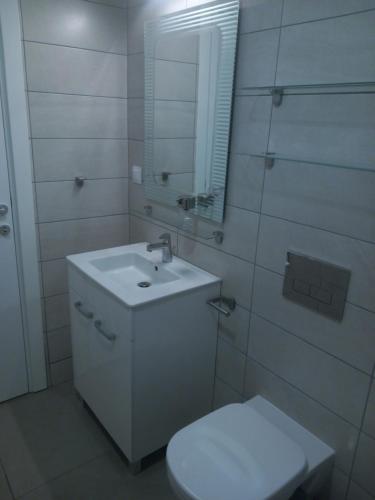 a white bathroom with a sink and a toilet at Zeirene in Skopje