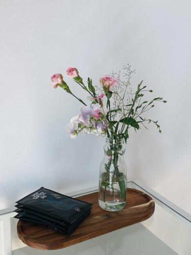 a vase of flowers on a table with a book at powiew - adults only b&b pensjonat noclegi Świnoujście - Unterkunft Swinemünde - guesthouse tennis garden breakfast at baltic sea in Świnoujście