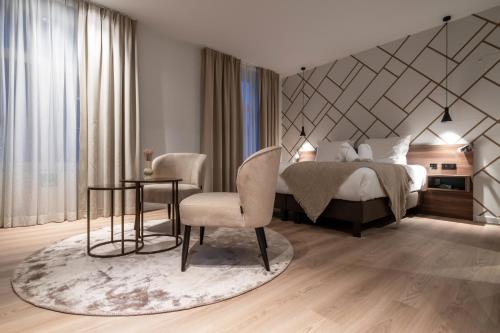 a bedroom with a bed and a chair and a table at ONE TWO FOUR - Hotel & Spa in Ghent