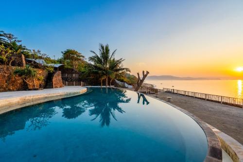 einen Pool mit Sonnenuntergang über dem Wasser in der Unterkunft Inlight Lombok Beach Hotel in Kuta Lombok