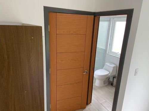a bathroom with a wooden door and a toilet at Casa Nueva en Parcela de Agrado in Valdivia