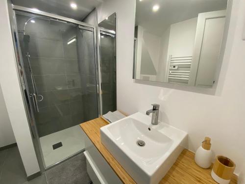 a white bathroom with a sink and a shower at Maison « Shaka » in Capbreton