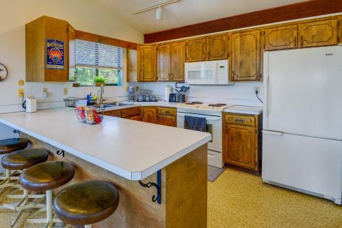 a kitchen with wooden cabinets and a white refrigerator at Westport Retreat with Pool Table Walk to State Park in Westport