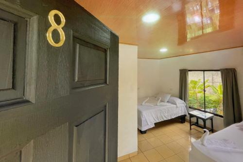 ein Zimmer mit einem Bett und einer Tür mit der Nummer acht in der Unterkunft Carey Lodging in Tortuguero