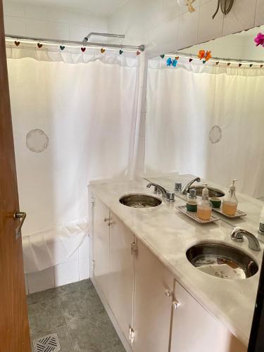 a white bathroom with two sinks and a shower at Pintoresca casa con pileta in Yala