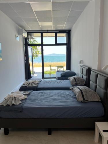 two beds in a room with a view of the ocean at Aliara Dilara Beach Apartments in Pomorie