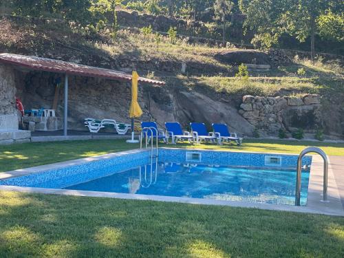 a swimming pool with blue chairs next to a house at Quintinha de Pinouco in Resende