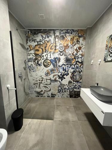 a bathroom with a wall covered in graffiti at Aliara Dilara Beach Apartments in Pomorie