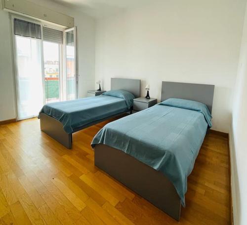 2 bedden in een witte kamer met houten vloeren bij Vera House - Big solution in Brescia
