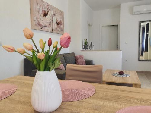 杜格普利耶的住宿－Apartment Radoš，白色花瓶,桌子上放着粉红色和黄色的花