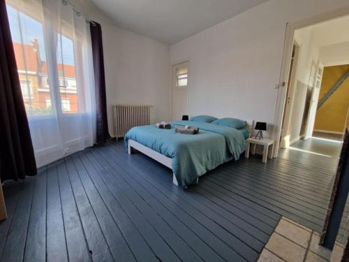 une chambre avec un lit et une grande fenêtre dans l'établissement Appartement duplex Coudekerque-Branche, à Coudekerque-Branche