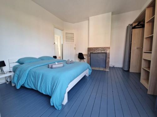 une chambre avec un lit bleu et une cheminée dans l'établissement Appartement duplex Coudekerque-Branche, à Coudekerque-Branche