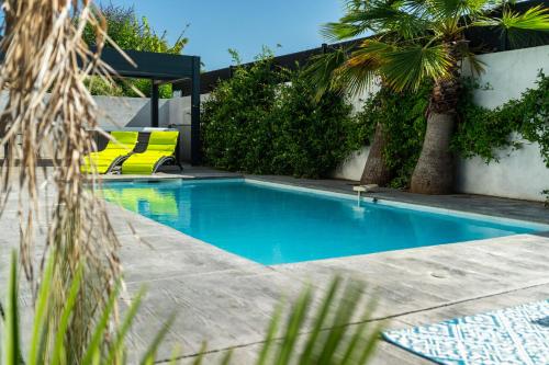 uma piscina com duas cadeiras amarelas e árvores em SUD VILLA DE LUXE - PLAGES - PISCINE - JACUZZI - Jeux Olympiques 2024 em Lattes