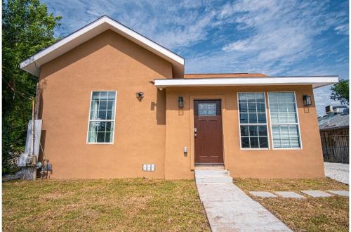 a house with a brown door on a yard at Charming 3BR2BA Gem Close to Downtown Riverwalk in San Antonio
