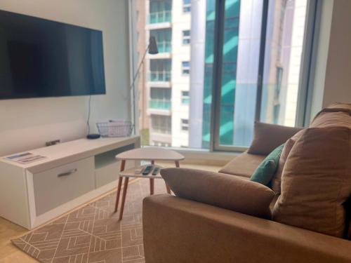 a living room with a couch and a flat screen tv at Luxury 1 Bed - City Suites Ocean Spa Plaza in Gibraltar