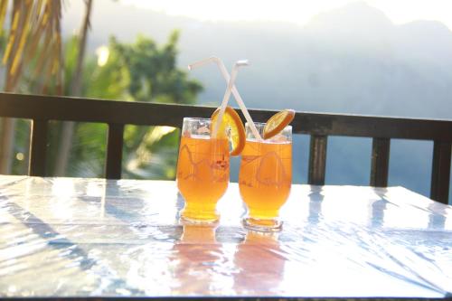 two glasses of orange juice sitting on a table at Different View in Ella