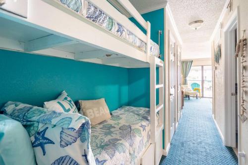 a bedroom with blue walls and bunk beds at GypSEA Blu Beach Condo Steps to the Beach in Galveston