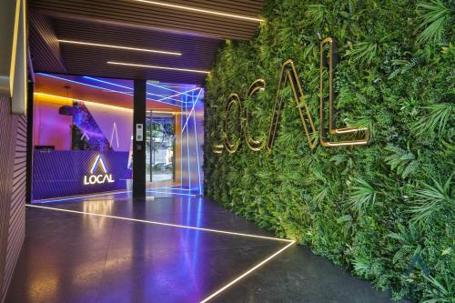 a hotel lobby with a green wall with a neon sign at Be Local Aparthotel in Mexico City