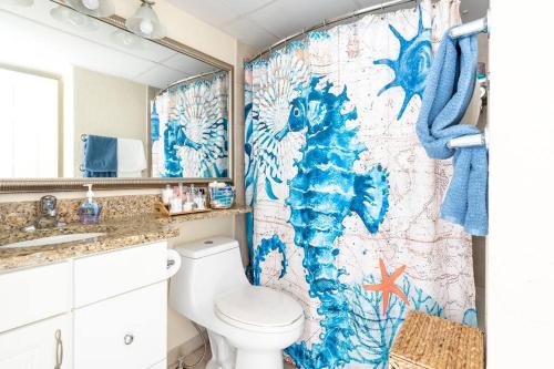 a bathroom with a toilet and a shower curtain at GypSEA Blu Beach Condo Steps to the Beach in Galveston