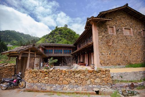 a stone house with a motorcycle parked in front of it at Dinh Đá H'Mông - Karsterly Rock Lodge in Dồng Văn