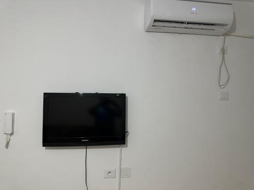einen Flachbild-TV, der an einer weißen Wand hängt in der Unterkunft Sousse Beach luxe in Harqalah