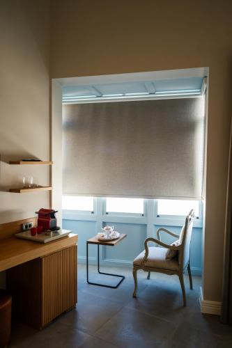 a room with a chair and a window with a blind at Zena Hotel Alaçatı Adults Only in Alacati