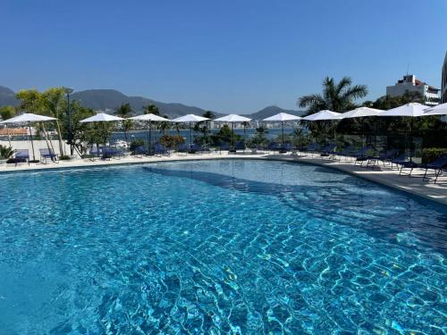 a large swimming pool with chairs and umbrellas at Grand Depa Bellomar in Acapulco