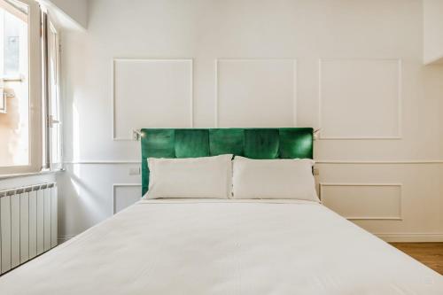 a white bed with a green headboard in a room at APT ROME - Vittoria Palace in Rome