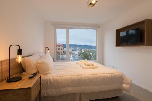 a bedroom with a bed and a large window at Austral Departamentos in Ushuaia