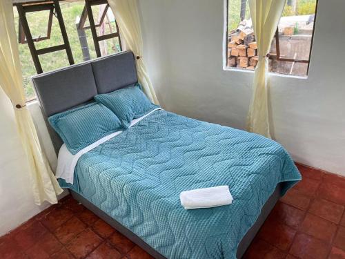 a bed with a blue comforter in a bedroom at Casa campestre Ubate in Ubaté