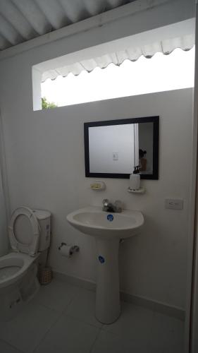 a bathroom with a sink and a toilet and a mirror at FINCA VILLA MAGALY en medio de la Naturaleza in Melgar