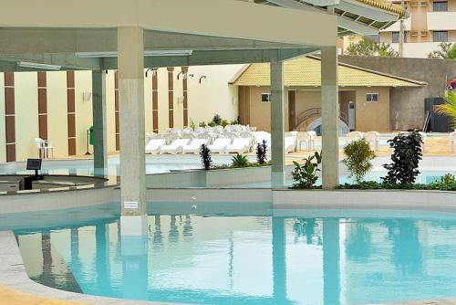 una piscina en un hotel con mesas y sillas en Via Caldas Exclusive, en Caldas Novas