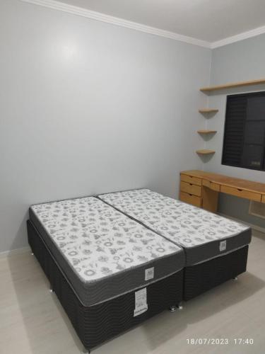 a bed sitting in a room next to a desk at Casa 4 quartos com piscina in Marechal Cândido Rondon