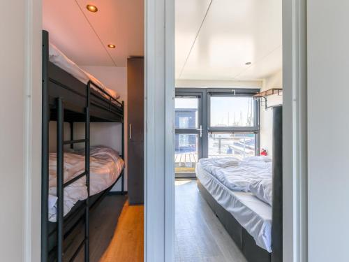 2 Etagenbetten in einem Zimmer mit Fenster in der Unterkunft Tiny houseboat Parel I - airco in Uitgeest