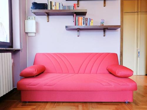 a pink couch in a living room with a book shelf at [Oltrepo'] Dimora nei vigneti vicino a Ics Maugeri in Santa Maria della Versa