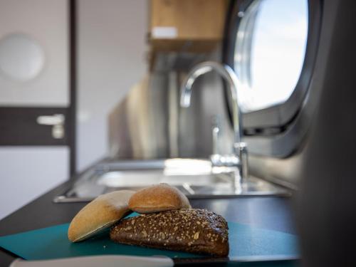 two loaves of bread sitting on a counter next to a sink at Tiny Houseboat De Woudaap - I in Uitgeest