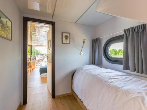 um quarto com uma cama branca e uma janela em Tiny Houseboat De Woudaap - I em Uitgeest