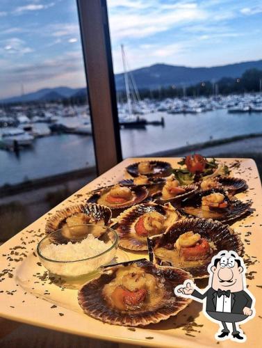 a table with plates of food on it with a view of a harbor at Apartamento flotante Unico C15A01 in Santander