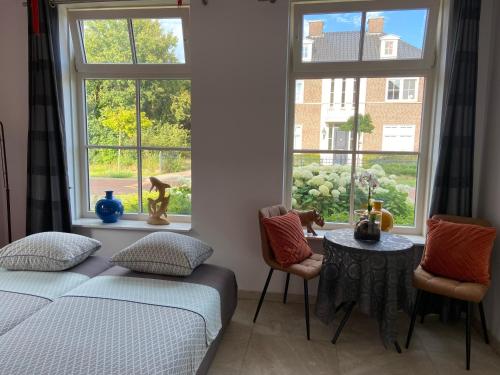 a bedroom with a bed and a table and windows at No Bathroom B&B in Aalten