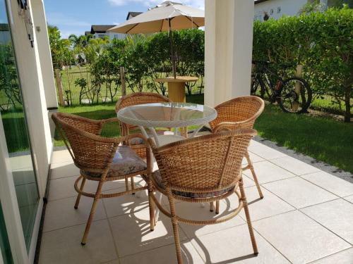 een tafel en stoelen op een patio met een parasol bij Apartamento Particular de 03 suítes, Resort Treebies, Praia de Subauma - Ba in Entre Rios