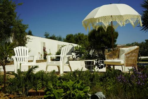 twee witte stoelen en een parasol in de tuin bij Residence Girasole in Giovinazzo