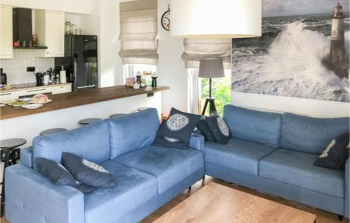 a living room with two blue couches and a kitchen at 2 Bedroom Beach Front Apartment In Rydzewo in Rydzewo