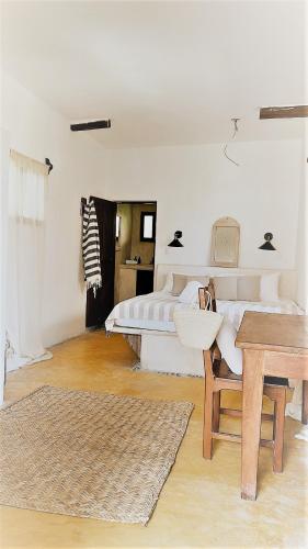 a white room with a bed and a table and a desk at La Conchita Tulum in Tulum