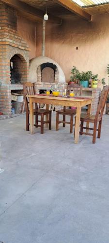 een houten tafel met twee stoelen en een bakstenen oven bij Hospedaje San Cayetano in Maimará